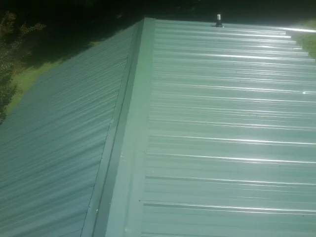 New green metal panels meeting at the ridge of a roof — Flat Roof Repair work by our crew in Campbelltown