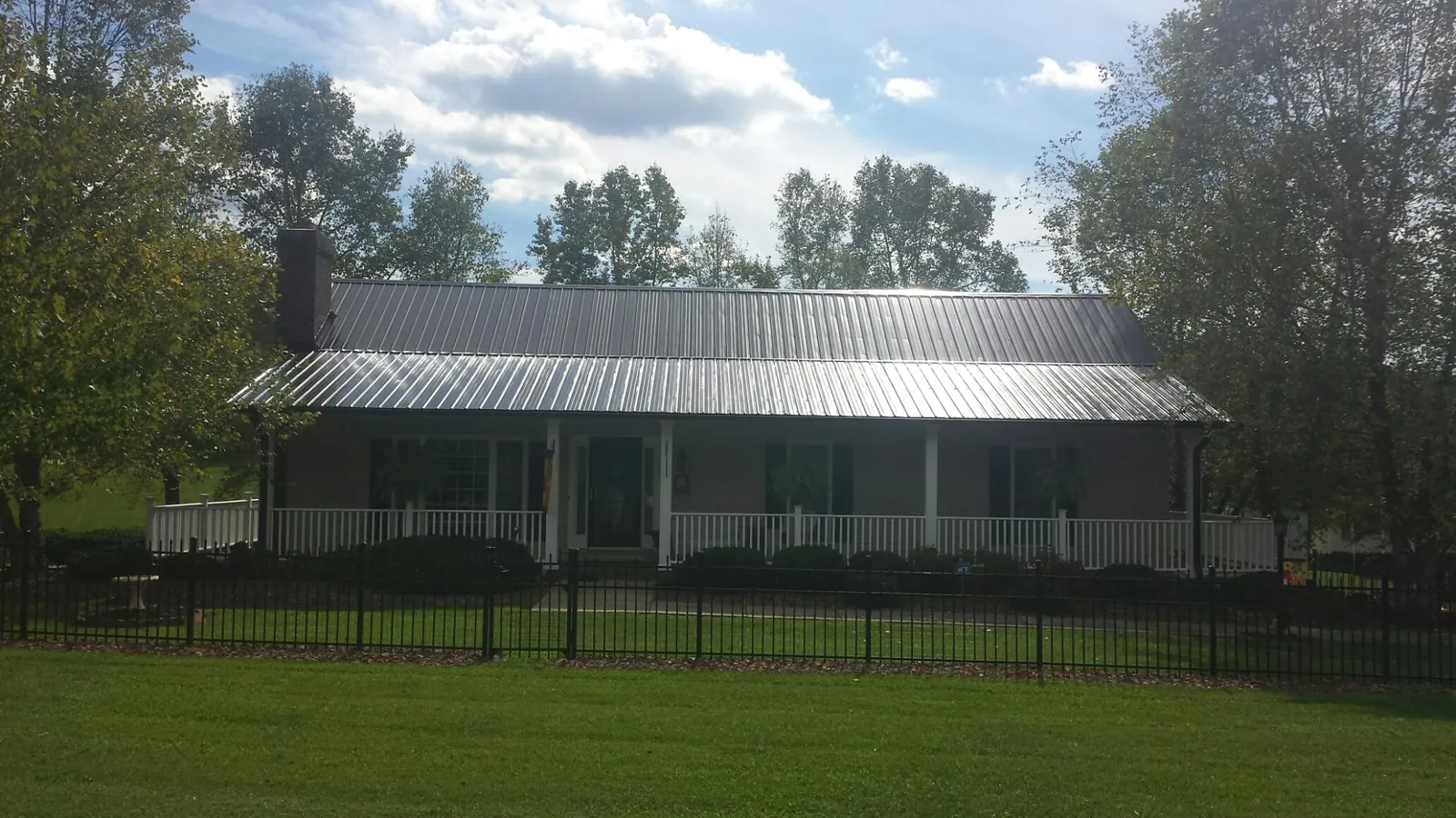 Gray metal roof on a brick ranch with a full width front porch — Gutter Guard Installation work by our crew in Campbelltown