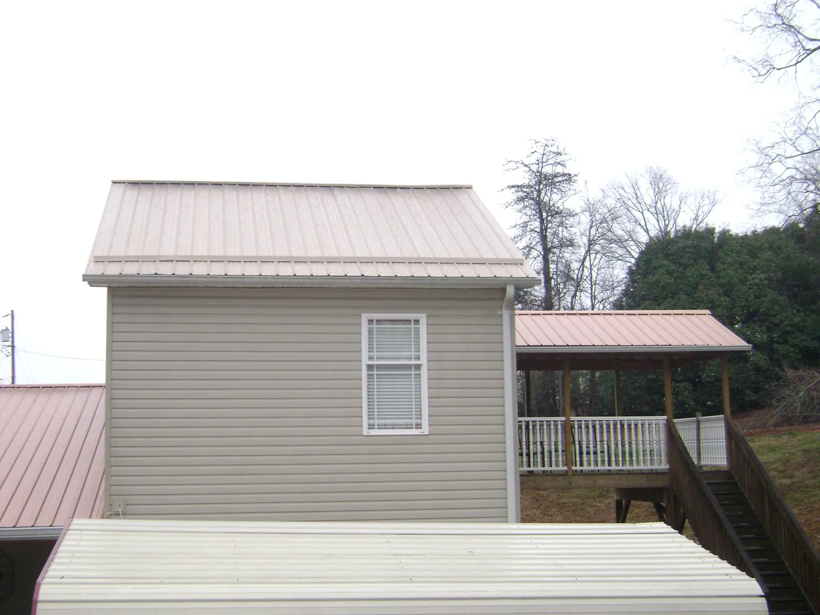 Tan metal roofs on a two story addition and attached porch, from a Roof Replacement job in Campbelltown