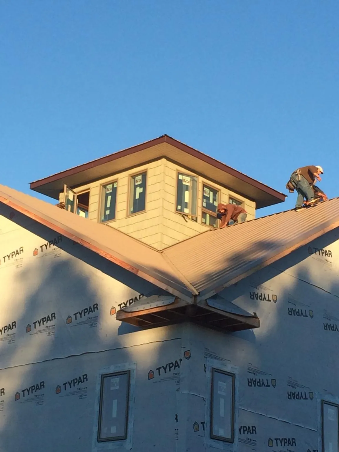 Roofers working around a rooftop cupola on a new metal roof at sunset — Roof Waterproofing in Campbelltown by Roofing Brothers